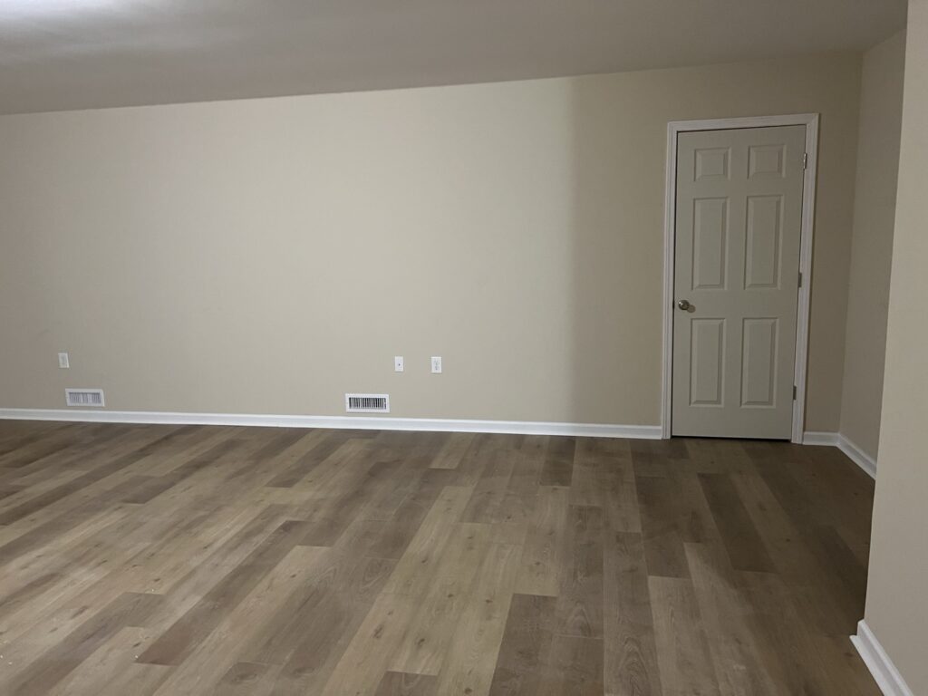 Completed living room with new laminate plank flooring and neutral walls after professional installation in Ocala, FL.