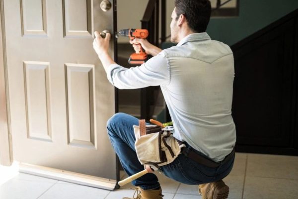 Professional handyman fixing residential door lock with drill Handyman installing a new door lock using a power drill during a home repair service in Marion County, Florida.